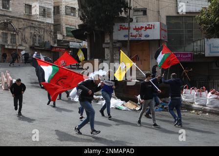 Hebron. 24. Februar 2023. Die Palästinenser fliehen aus Tränengaskanistern, die von israelischen Streitkräften während der Zusammenstöße in der Stadt Hebron im Westjordanland am 24. Februar 2023 abgefeuert wurden. Kredit: Mamoun Wazwaz/Xinhua/Alamy Live News Stockfoto
