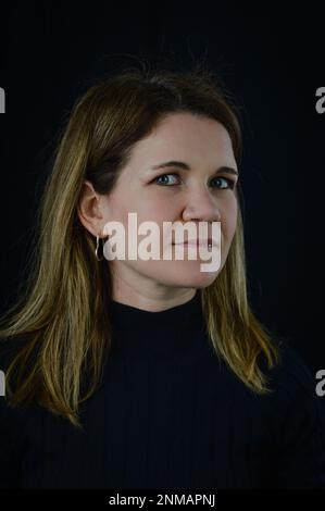 Porträt einer schönen blonden Frau mittleren Alters in einem schwarzen Pullover auf schwarzem Hintergrund Stockfoto