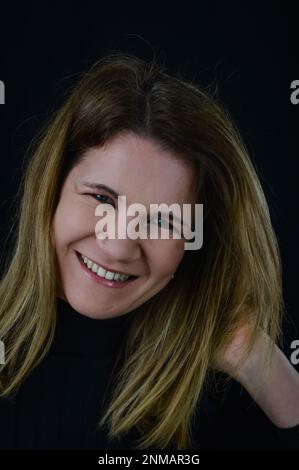 Porträt einer schönen blonden Frau, die fröhlich lacht, während sie ihr Haar anpasst Stockfoto