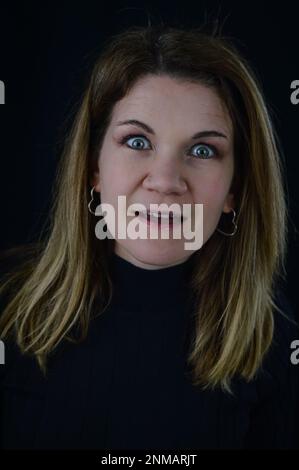 Porträt einer schönen blonden Frau, die erstaunt und klaffend aussieht Stockfoto
