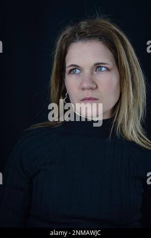 Porträt einer schönen blonden Frau mit einem traurigen Blick, die im All wegschaut Stockfoto