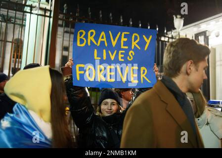 Warschau, Warschau, Polen. 24. Februar 2023. Eine Frau hat am 24. Februar 2023 in Warschau, Polen, ein Plakat mit der Aufschrift "Tapferkeit ist für immer". Hunderte von Menschen versammelten sich außerhalb der russischen Botschaft, um gegen die jahrelange russische Aggression gegen die Ukraine zu protestieren und an diejenigen zu erinnern, die ihr Leben verloren haben. (Kreditbild: © Aleksander Kalka/ZUMA Press Wire) NUR REDAKTIONELLE VERWENDUNG! Nicht für den kommerziellen GEBRAUCH! Stockfoto