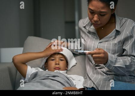 Eine besorgte Frau sieht sich die Thermometerwerte an Stockfoto