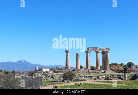 Die Ruinen des Apollotempels im antiken Korith Griechenland mit einer Kirche und einem Dorf und hohen Bergen im Hintergrund Stockfoto