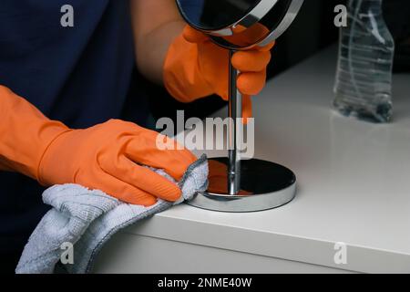 Nahaufnahme der Frauenhände in orangefarbenen Gummihandschuhen zur Reinigung der weißen Wickelfläche Stockfoto