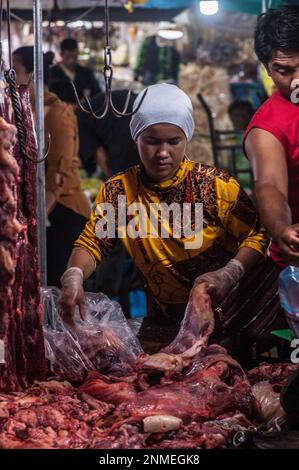 Eine muslimische Frau bereitet rohes Fleisch für den Verkauf auf dem wichtigsten Gemüse- und Fleischgroßmarkt, Phsar Dumkor, nachts in Phnom Penh, Kambodscha, zu. © Kraig Stockfoto