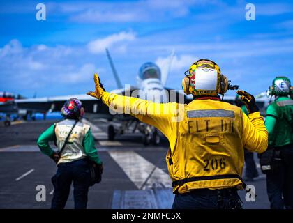 230224-N-MH015-2021 PHILIPPINE SEA (24. FEBRUAR 2023) A U.S. Navy Sailor leitet eine F/A-18F Super Hornet von den ‚Fighting Redcocks‘ der Streikkkämpfer-Staffel (VFA) 22 auf dem Cockpit des Flugzeugträgers USS Nimitz (CVN 68). Nimitz ist in der US-7.-Flotte und führt Routineeinsätze durch. 7. Fleet sind die USA Die größte Flotte der Navy, die mit einer Anzahl von Flotten ausgestattet ist, und arbeitet regelmäßig mit Alliierten und Partnern zusammen, um eine freie und offene Region im Indo-Pazifik zu erhalten. (USA Marinefoto von Mass Communication Specialist 3. Klasse Joseph Calabrese) Stockfoto