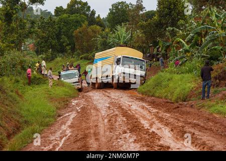 Ein Lastwagen, der nach Regen in Uganda im Schlamm auf einer schlammigen Straße steckte. Regen macht unbefestigte Straßen schlammig. Stockfoto