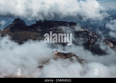 Meteo-Station auf dem Kasprowy Wierch und Giewont-Gipfel im Hintergrund, die von Wolken für einen Bruchteil einer Sekunde freigelegt wird, Tatra-Gebirge, Polen Stockfoto