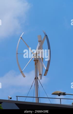 Der Windturbinengenerator befindet sich auf dem Dach eines Gebäudes mit blauem Himmel, Melbourne Australia. Stockfoto