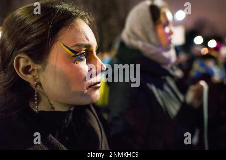 Während des Anti-Kriegs-Protests in Warschau ist eine Demonstrantin mit der ukrainischen Flagge auf ihrem Gesicht zu sehen. Tausende Polen, Ukrainer und Belarussen haben sich am Jahrestag des Angriffs vor der russischen Botschaft in Warschau versammelt, um gegen Russlands Aggression gegen die Ukraine zu protestieren und Solidarität mit der Ukraine zu zeigen. Demonstranten hielten ihre nationale Flagge und auch Schilder mit den geschriebenen Namen der im Krieg gefallenen Ukrainer. Die Menge marschierte später ins parlament, um Druck auf die weitere Unterstützung der Ukraine und die Verurteilung des Krieges auszuüben. (Foto: Attila Husejnow/SOPA Images/Sipa USA) Stockfoto
