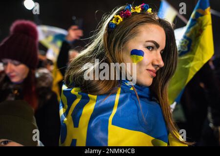 Während des Anti-Kriegs-Protests in Warschau wird eine Frau mit der ukrainischen Flagge auf ihrem Gesicht gesehen. Tausende Polen, Ukrainer und Belarussen haben sich am Jahrestag des Angriffs vor der russischen Botschaft in Warschau versammelt, um gegen Russlands Aggression gegen die Ukraine zu protestieren und Solidarität mit der Ukraine zu zeigen. Demonstranten hielten ihre nationale Flagge und auch Schilder mit den geschriebenen Namen der im Krieg gefallenen Ukrainer. Die Menge marschierte später ins parlament, um Druck auf die weitere Unterstützung der Ukraine und die Verurteilung des Krieges auszuüben. (Foto: Attila Husejnow/SOPA Images/Sipa USA) Stockfoto