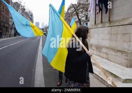 London, Großbritannien. 24. Februar 2023. Eine Frau läuft mit einer ukrainischen Flagge in Whitehall gegenüber der Downing Street in London. Die Welt begeht heute den einjährigen Jahrestag der massiven russischen Invasion in der Ukraine. Kredit: SOPA Images Limited/Alamy Live News Stockfoto