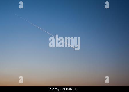 Die Spur des Flugzeugs am Himmel, am klaren Nachthimmel, blieb die Spur des fliegenden Flugzeugs in der Ferne Stockfoto