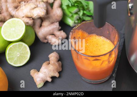 Drücken Sie Karottensaft mit Entsafter gesunde Zitrusfrüchte im Hintergrund. Einnahme Vitamine Entgiftung, gesunde Ernährung und Lebenskonzept. Stockfoto