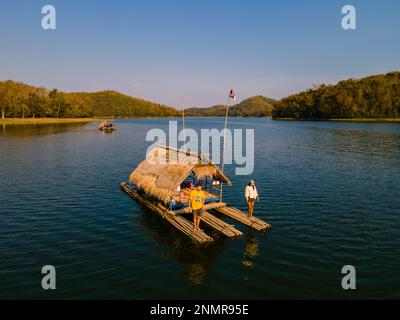 Ein paar europäische Männer und asiatische Frauen besuchen den Huai Krathing Lake im Nordosten Thailands, berühmt für seine schwimmenden Bambusfloßboote, wo Sie mittags oder abends in der Mitte des Sees zu Mittag essen können. Stockfoto