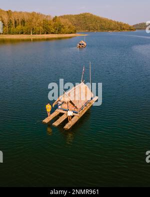 Ein paar europäische Männer und asiatische Frauen besuchen den Huai Krathing Lake im Nordosten Thailands, berühmt für seine schwimmenden Bambusfloßboote, wo Sie mittags oder abends in der Mitte des Sees zu Mittag essen können. Stockfoto