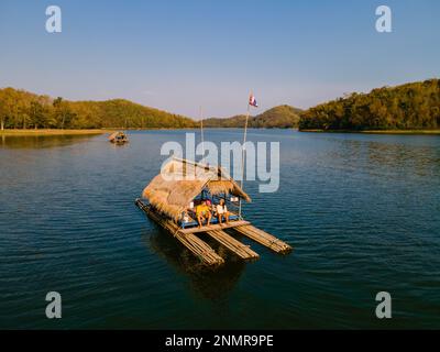 Ein paar europäische Männer und asiatische Frauen besuchen den Huai Krathing Lake im Nordosten Thailands, berühmt für seine schwimmenden Bambusfloßboote, wo Sie mittags oder abends in der Mitte des Sees zu Mittag essen können. Stockfoto