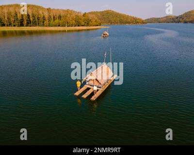 Ein paar europäische Männer und asiatische Frauen besuchen den Huai Krathing Lake im Nordosten Thailands, berühmt für seine schwimmenden Bambusfloßboote, wo Sie mittags oder abends in der Mitte des Sees zu Mittag essen können. Stockfoto