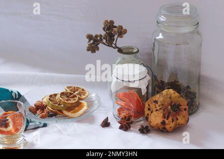 Getrocknete Zitronenscheiben und Aromaten auf einer Platte zur Vorbereitung auf eine entspannende Aromatherapie zu Hause Stockfoto