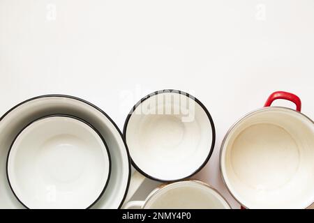 Verschiedene gebrauchte emaillierte Küchentöpfe auf weißem Hintergrund, ein Set Töpfe und eine Schüssel Weiß Stockfoto