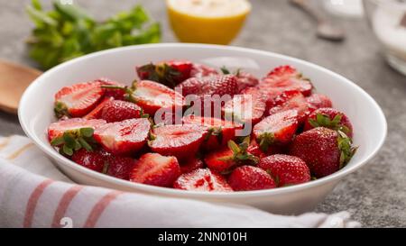 Nahaufnahme reifer Erdbeeren in weißen Scheiben auf dem Tisch Stockfoto