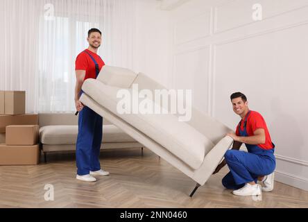 Professionelle Umzugsleute, die ein Sofa im neuen Haus tragen Stockfoto