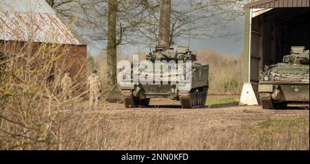 Zwei Soldaten stehen vor Warrior FV510 Infanterie Kampffahrzeugen, Wilts UK Stockfoto