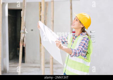 Asiatische Ingenieurarbeiterin auf der Baustelle. Schlaue Architektin im Sicherheitsbereich, die arbeitet. Stockfoto