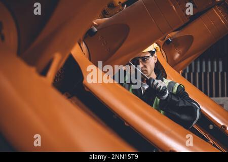 Serviceteam des Ingenieurs repariert den Schweißarm des Roboters in der Automatisierungsfabrik. Mitarbeiter arbeiten in der Roboterarmmontage in der Schwermetallindustrie. Stockfoto