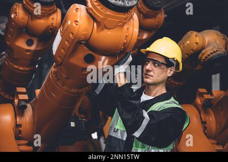 Serviceteam des Ingenieurs repariert den Schweißarm des Roboters in der Automatisierungsfabrik. Mitarbeiter arbeiten in der Roboterarmmontage in der Schwermetallindustrie. Stockfoto