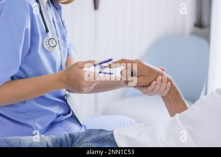 Die Arzthelferin in der Nahaufnahme misst mit dem Pausenoxymeter der Fingerspitze den Sauerstoffsättigungsgrad des Blutes mit dem Patienten Stockfoto