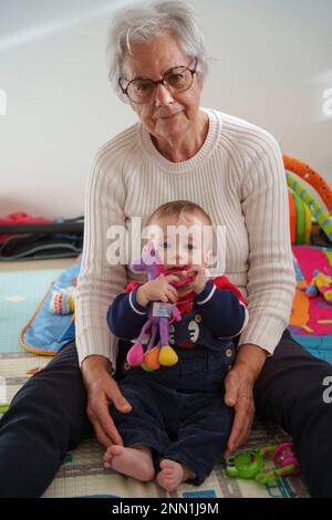 Porträt Baby sitzt auf dem Boden und spielt mit seiner Großmutter zu Hause Stockfoto