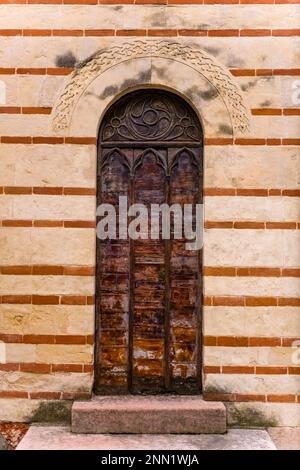 Eine alte hölzerne Eingangstür im Innenhof der Scaliger-Gräber, Arche Scaligere, im historischen Teil von Verona. Stockfoto