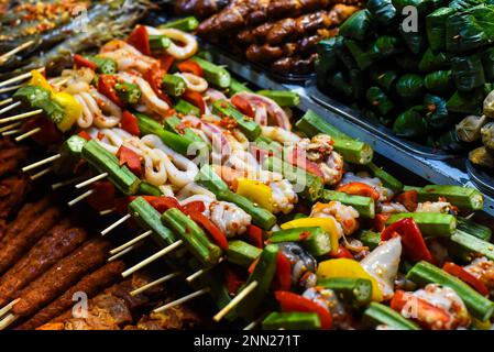 Viele rohe Tintenfische auf Spießen und Meeresfrüchte auf dem vietnamesischen Nachtmarkt in Da Lat Stockfoto