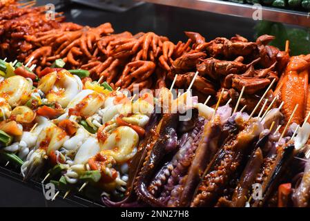 Viele rohe Tintenfische auf Spießen und Meeresfrüchte auf dem vietnamesischen Nachtmarkt in Da Lat Stockfoto