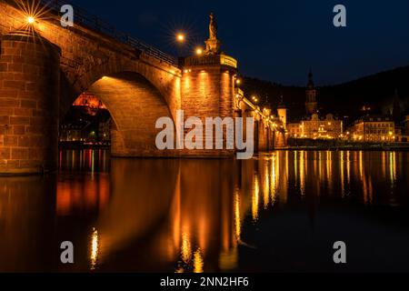 Die Altstadt von Heidelberg mit der Alten Brücke, dem Fluss Neckar und dem Brückentor bei Nacht. Das Bild stammt aus der Öffentlichkeit. Deutschland. Stockfoto