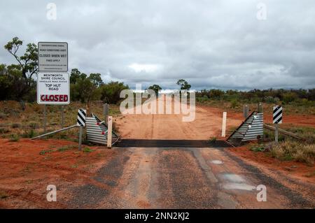 Pooncarie Australia, unbefestigte Straße und Straßensperrungsschild aufgrund von nassem Wetter im Outback Stockfoto