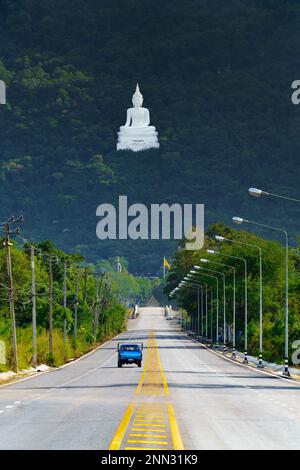 Buddha Sakolsima Mongkhon im Tempel Wat Thep phithak Punnaram. Der große weiße Buddha befindet sich hoch oben im Wald, von einem entfernten Aussichtspunkt aus gesehen. Stockfoto