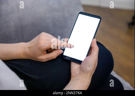 Smartphone in der Hand. Telefonmodell in weiblicher Hand mit weißem Bildschirm. Stockfoto