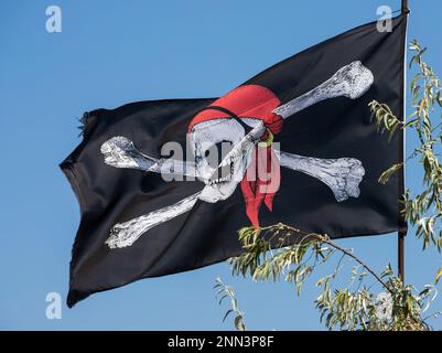 Ein Schädel mit Kreuz, Piratenflagge, die im Wind winkt. Stockfoto