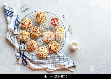 Miniportionen von Flammekueche oder Flammkuchen, französische und deutsche Spezialität, auf dem runden Kühlgitter aus Metall, Draufsicht Stockfoto