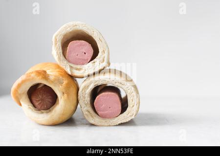 Würstchenrolle auf einem Marmortablett, gedrehte Würstchenrolle auf einem Marmortablett, große Schweine in einer Decke Stockfoto