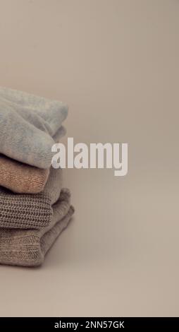 Gestrickte Pullover in warmen Pastellfarben mit verschiedenen Strickmustern, gefaltet im Stapel, Nahaufnahme, Platz für Text kopieren. Stockfoto
