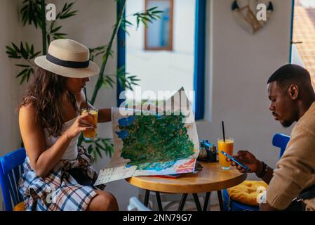 Zwei glückliche Touristen ruhen sich an einem sonnigen Tag in einer Bar mit ihren Säften auf dem Tisch aus Stockfoto