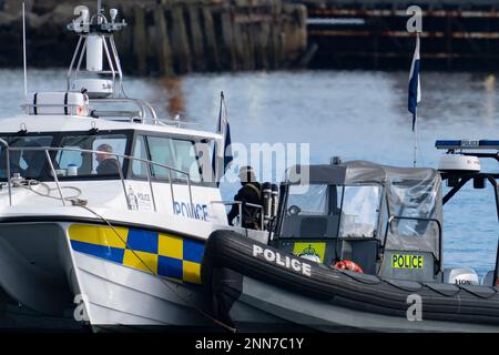 Greenock, Schottland, Großbritannien. 25. Februar 2023 Polizei und Pilot am Ort des Untergangs des Clyde Marine Services Tubs Biter, der gestern in Greenock in der Nähe des Ost-Indien-Hafens gesunken ist. Zwei Crewmitglieder werden immer noch vermisst. Bojen markieren die Stelle, an der der Schlepper gesunken ist. Iain Masterton/Alamy Live News Stockfoto