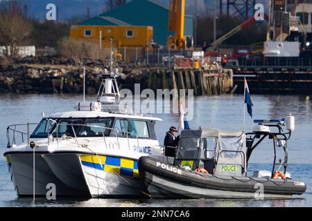 Greenock, Schottland, Großbritannien. 25. Februar 2023 Polizei und Pilot am Ort des Untergangs des Clyde Marine Services Tubs Biter, der gestern in Greenock in der Nähe des Ost-Indien-Hafens gesunken ist. Zwei Crewmitglieder werden immer noch vermisst. Bild: Polizeitaucher arbeiten über dem versunkenen Schlepper. Iain Masterton/Alamy Live News Stockfoto