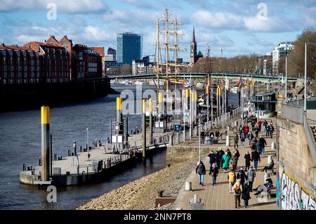 Bremen, Deutschland. 25. Februar 2023. Bei sonnigem Wetter laufen zahlreiche Menschen entlang der Promenade Schlachte an der Weser. Die Kulturkirche St. Stephani ist im Hintergrund zu sehen. Kredit: Hauke-Christian Dittrich/dpa/Alamy Live News Stockfoto