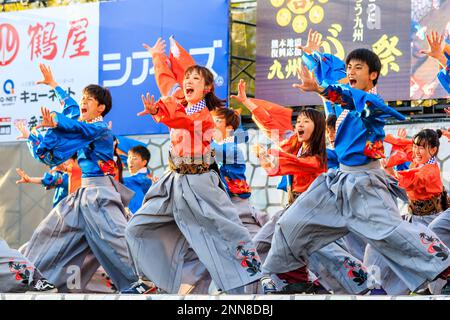 Ein japanisches Team junger Yosakoi-Tänzer tanzt auf der Bühne des alljährlichen Kyusyu Gassai Festivals in Kumamoto in Yukata-Langarm-Tuniken. Stockfoto