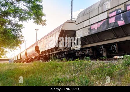 Low-Angle-Blick auf einen Güterzug, der bei Sonnenuntergang auf einem Rangierplatz steht Stockfoto
